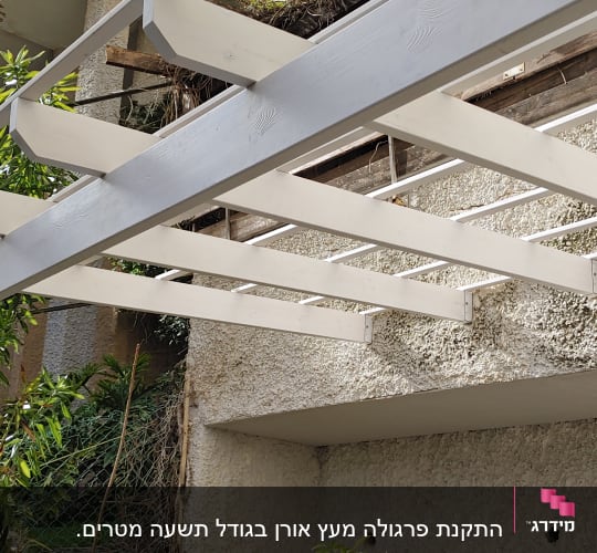 פרגולה מעץ לבן מחוברת לקיר בטון